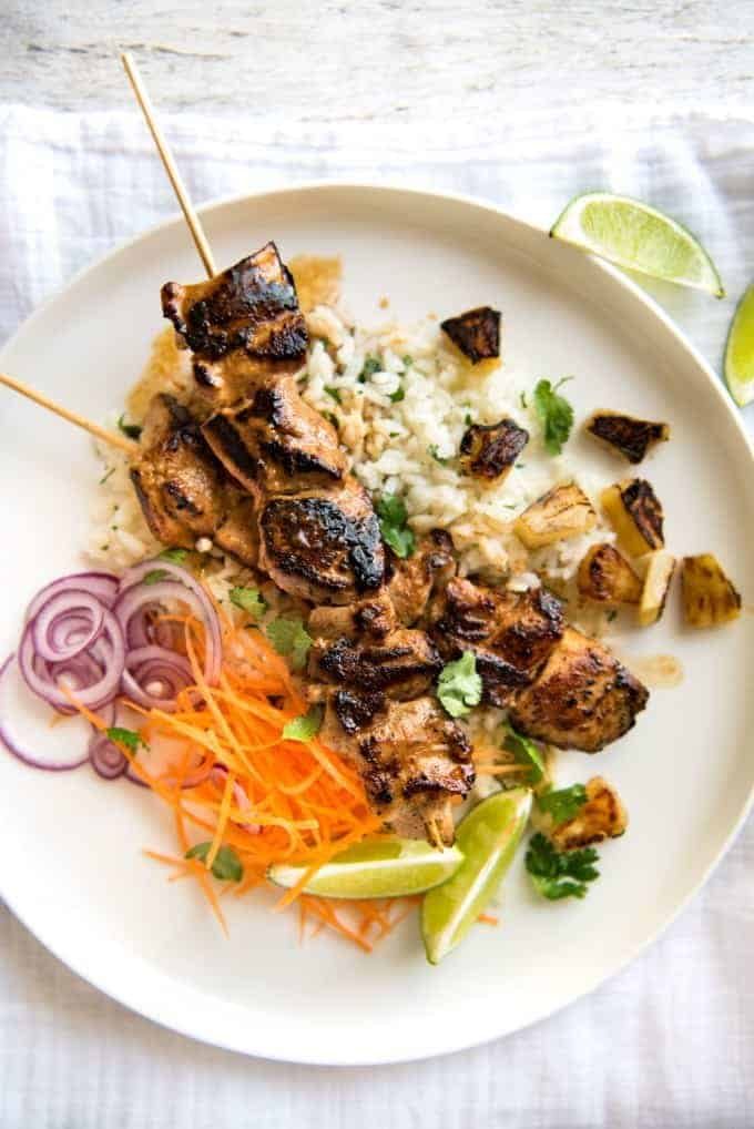 Pineapple Coconut Hawaiian Chicken Skewers on a white plate on top of coconut lime rice.