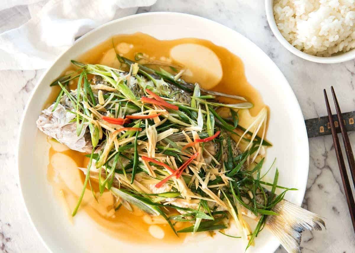 A Chinese Steamed Fish topped with Ginger and Shallots and seasonings, with hot oil poured over it to create a dramatic sizzle and an amazing sauce. So simple, yet so utterly delicious. Steam OR bake the fish! staging.recipetineats.com