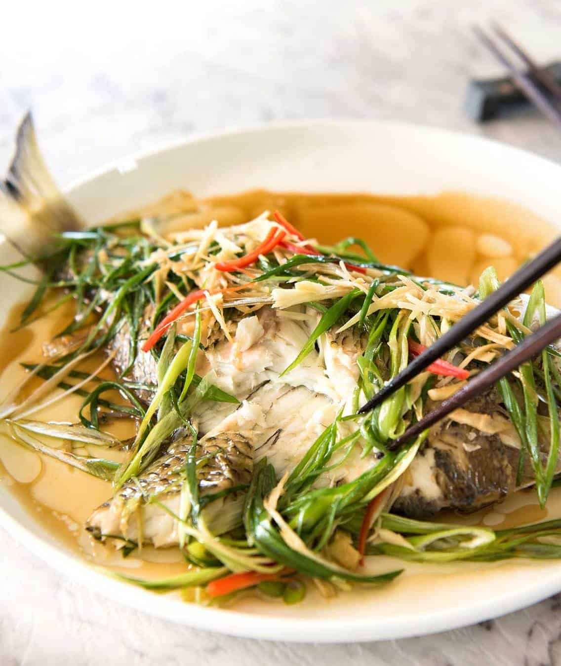 A Chinese Steamed Fish topped with Ginger and Shallots and seasonings, with hot oil poured over it to create a dramatic sizzle and an amazing sauce. So simple, yet so utterly delicious. Steam OR bake the fish! staging.recipetineats.com