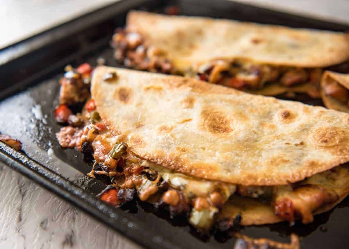 Crispy Oven Baked Chicken Quesadillas - This is how to make multiple Quesadillas at the same time! Crispy on the outside, stuffed with Mexican seasoned chicken and capsicum / bell peppers (and cheese of course!) staging.recipetineats.com