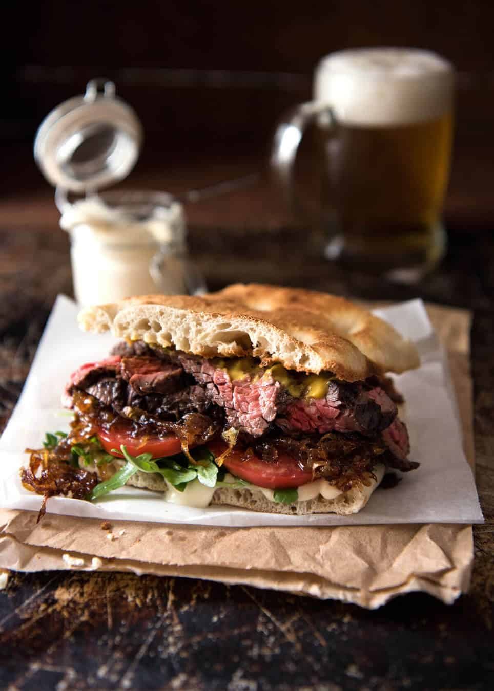 A juicy Steak Sandwich loaded with tender slices of steak, caramelised onion, garlic aioli, lettuce, tomato and mustard. staging.recipetineats.com