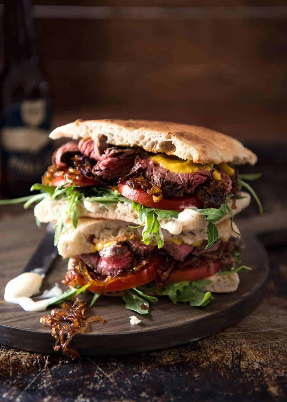 A juicy Steak Sandwich loaded with tender slices of steak, caramelised onion, garlic aioli, lettuce, tomato and mustard. staging.recipetineats.com
