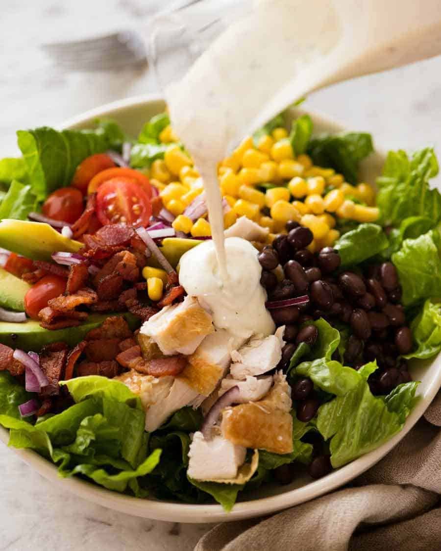 Yogurt Ranch Dressing being poured over SouthWest Chicken Salad