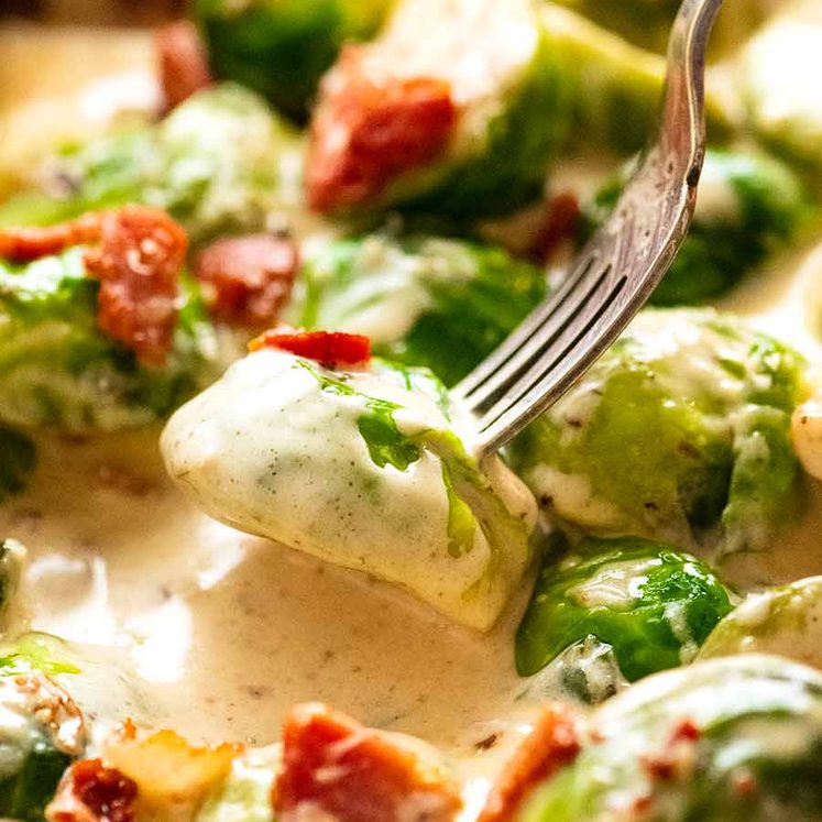 Fork picking up saut&eacute;ed Brussels sprouts in a creamy sauce
